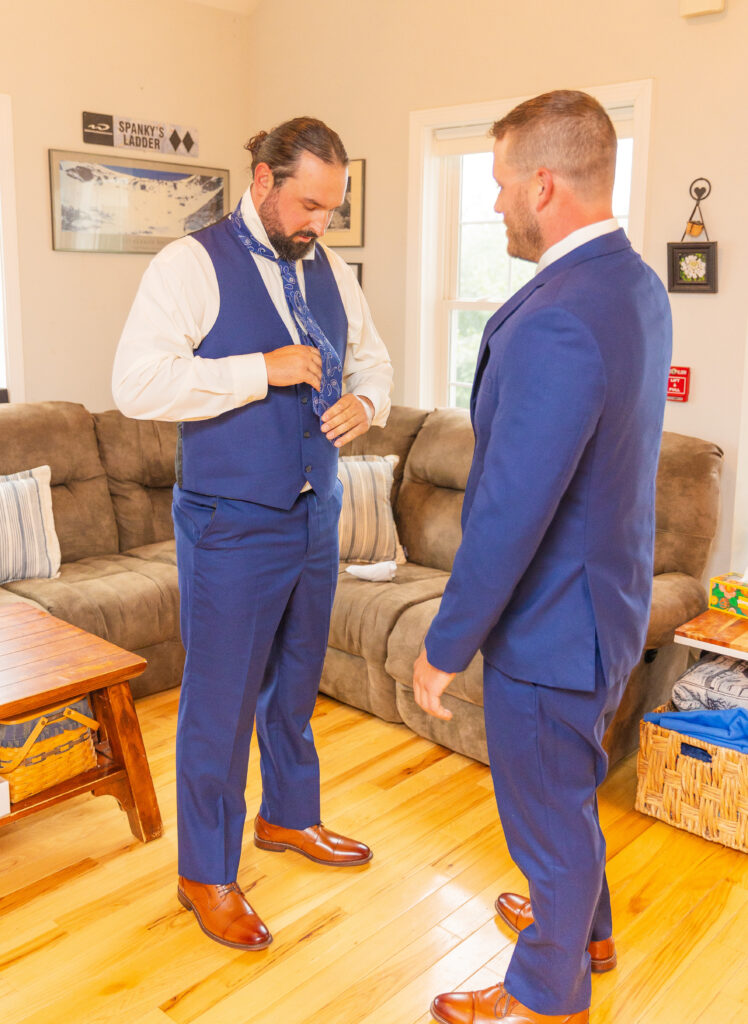 groom adjusts his tie with his groomsmen.