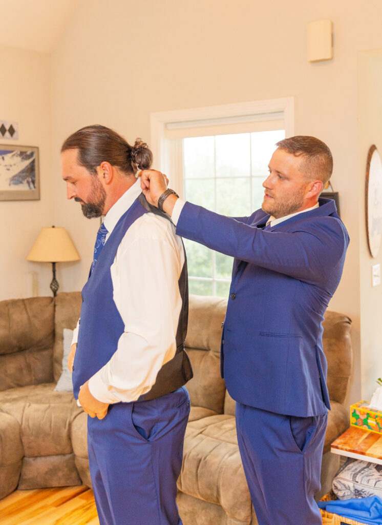 Groomsmen is adjusting the grooms collar.