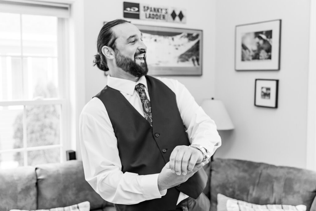 Groom laughs while putting on his cuff links.