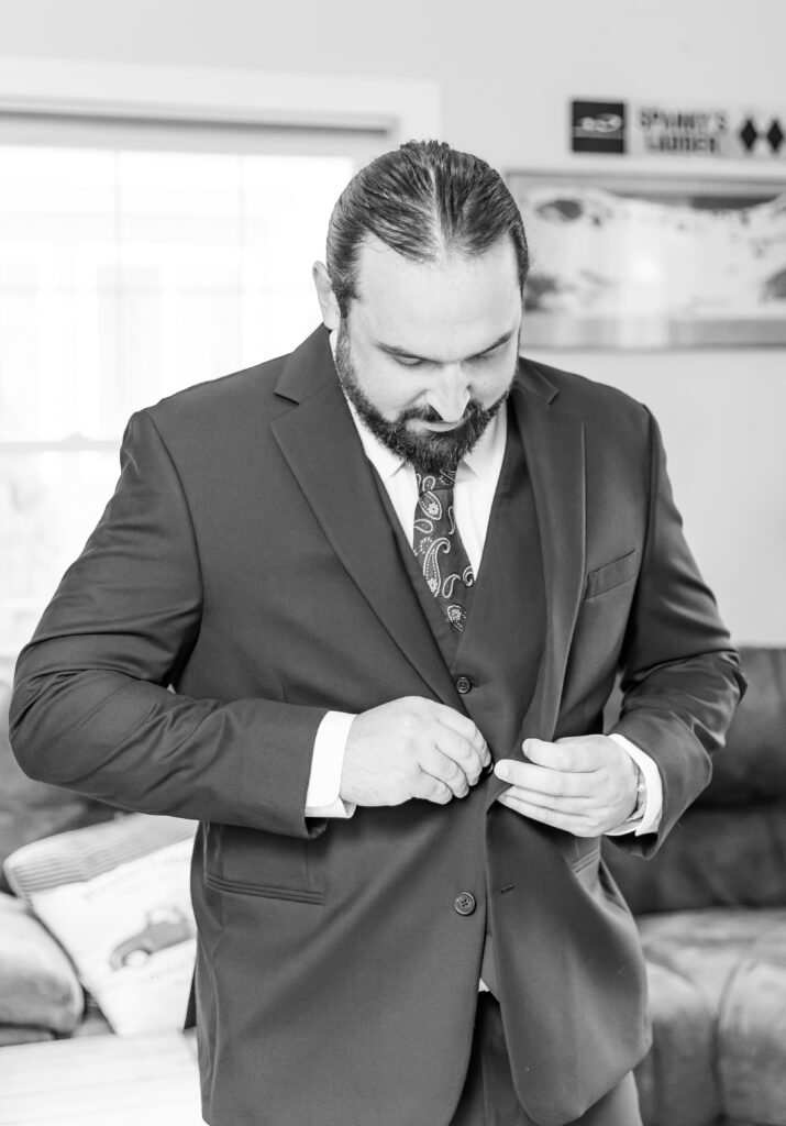 Groom buttoning his jacket