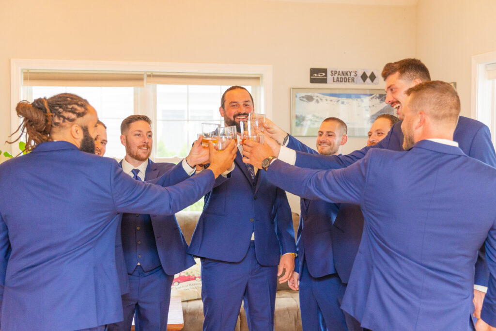 The groom and groomsmen pour shots for a cheers.