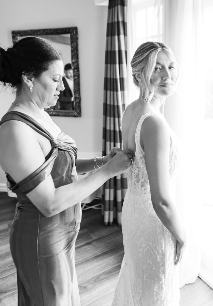 Mom helping the bride get into her dress