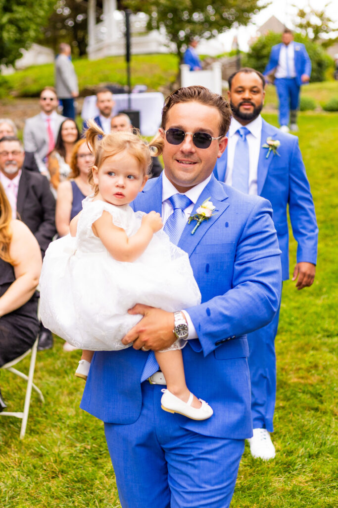 groomsmen and the brides daughter walking down the aisle