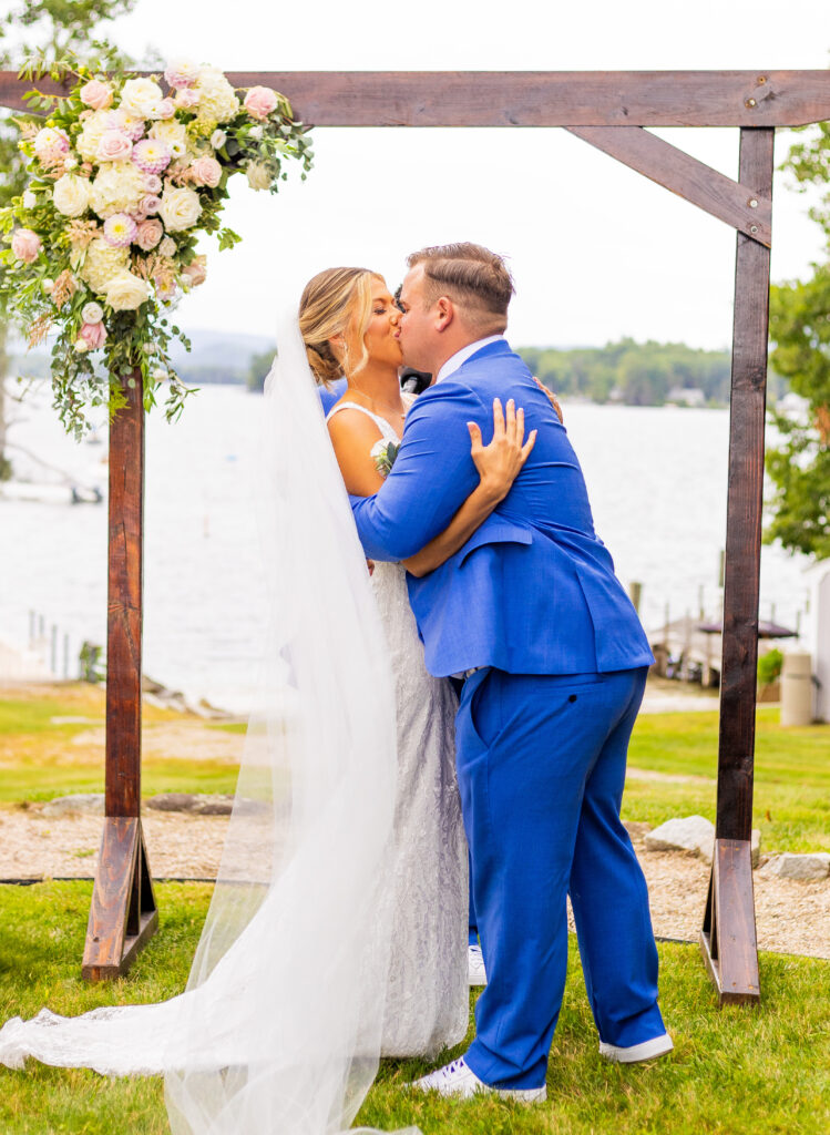 Bride and groom share their first kiss at their wedding on lake winnipesaukee in new hampshire