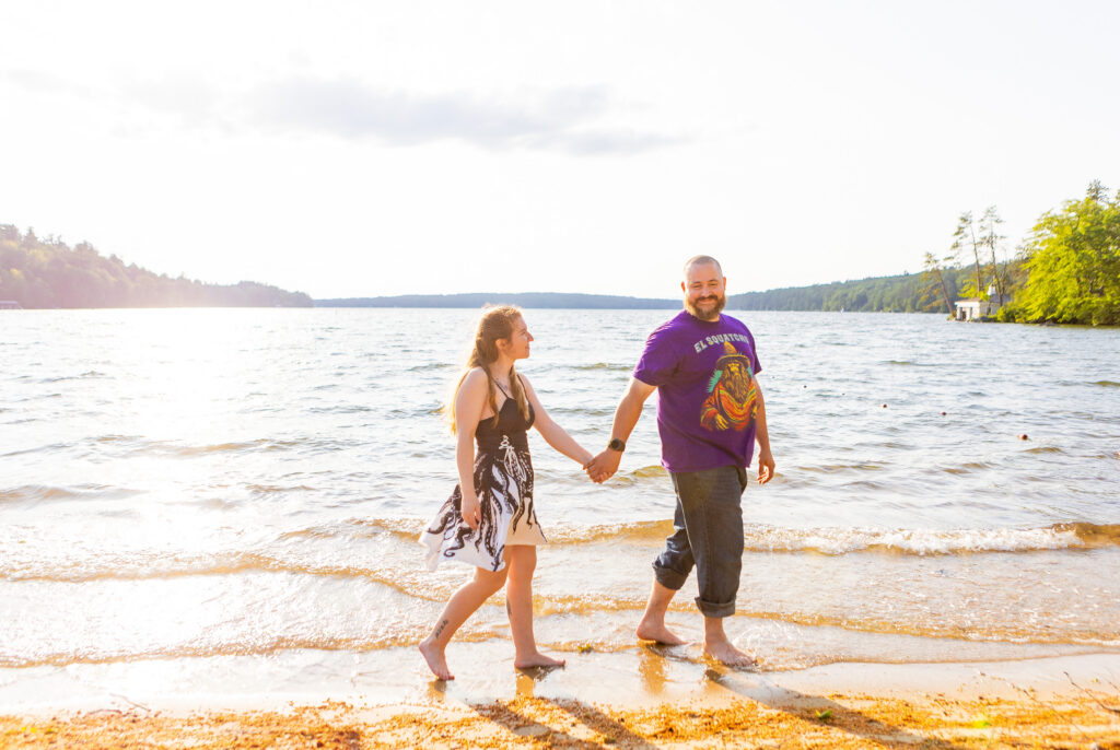 Couple walks along the shoreline of Lake Winnipesaukee in Wolfeboro, New Hampshire.